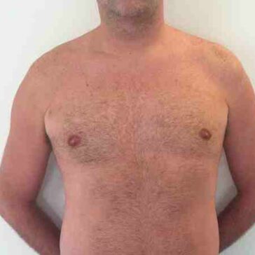Shirtless adult male standing with arms behind his back, facing forward against a plain white background.