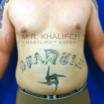 A person with the word "Spartan" and a geometric symbol tattooed on their bare abdomen against a blue background.