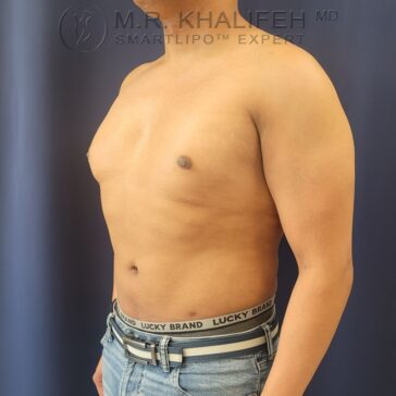 A shirtless person stands against a dark blue background, wearing light blue jeans and a Lucky Brand waistband, facing left in a profile view.