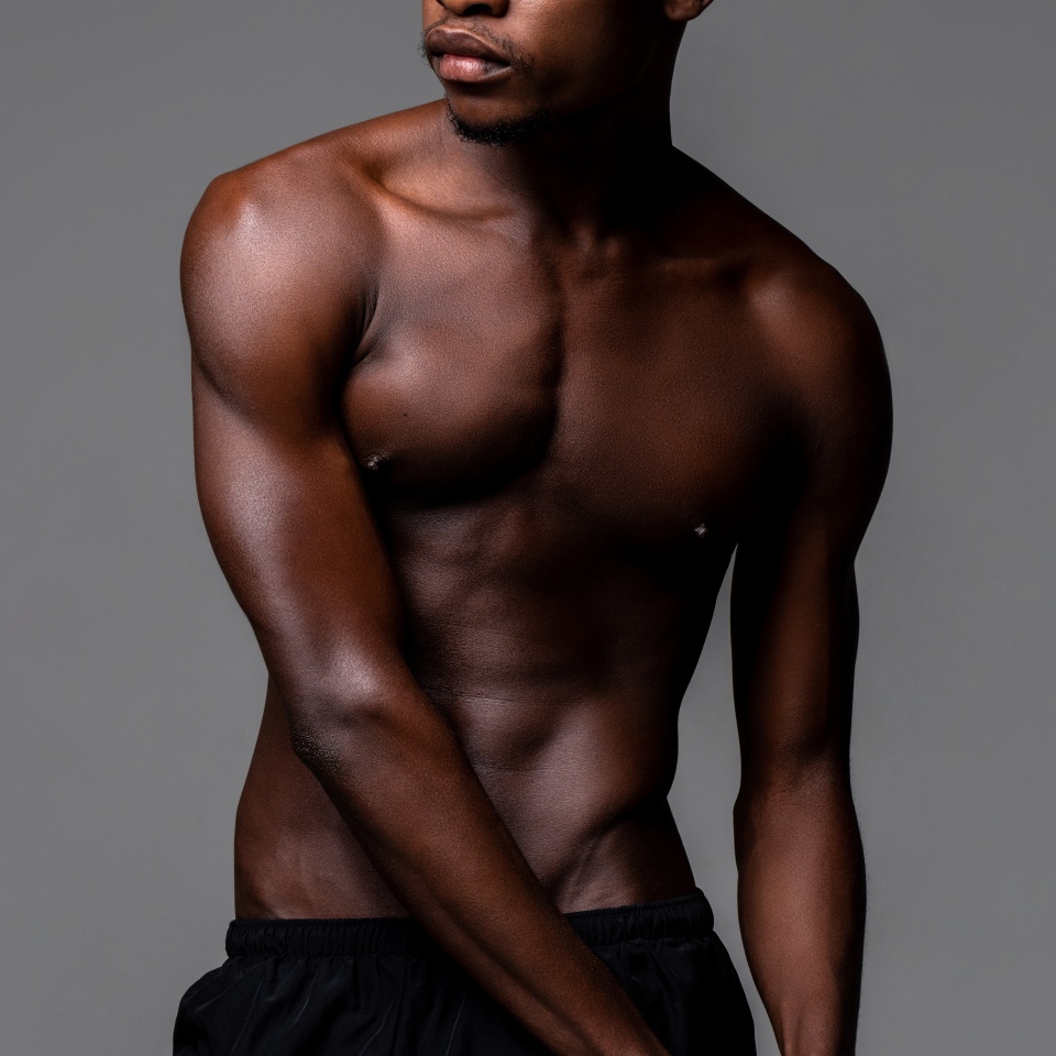 Nude lean young African man body in studio isolated gray background