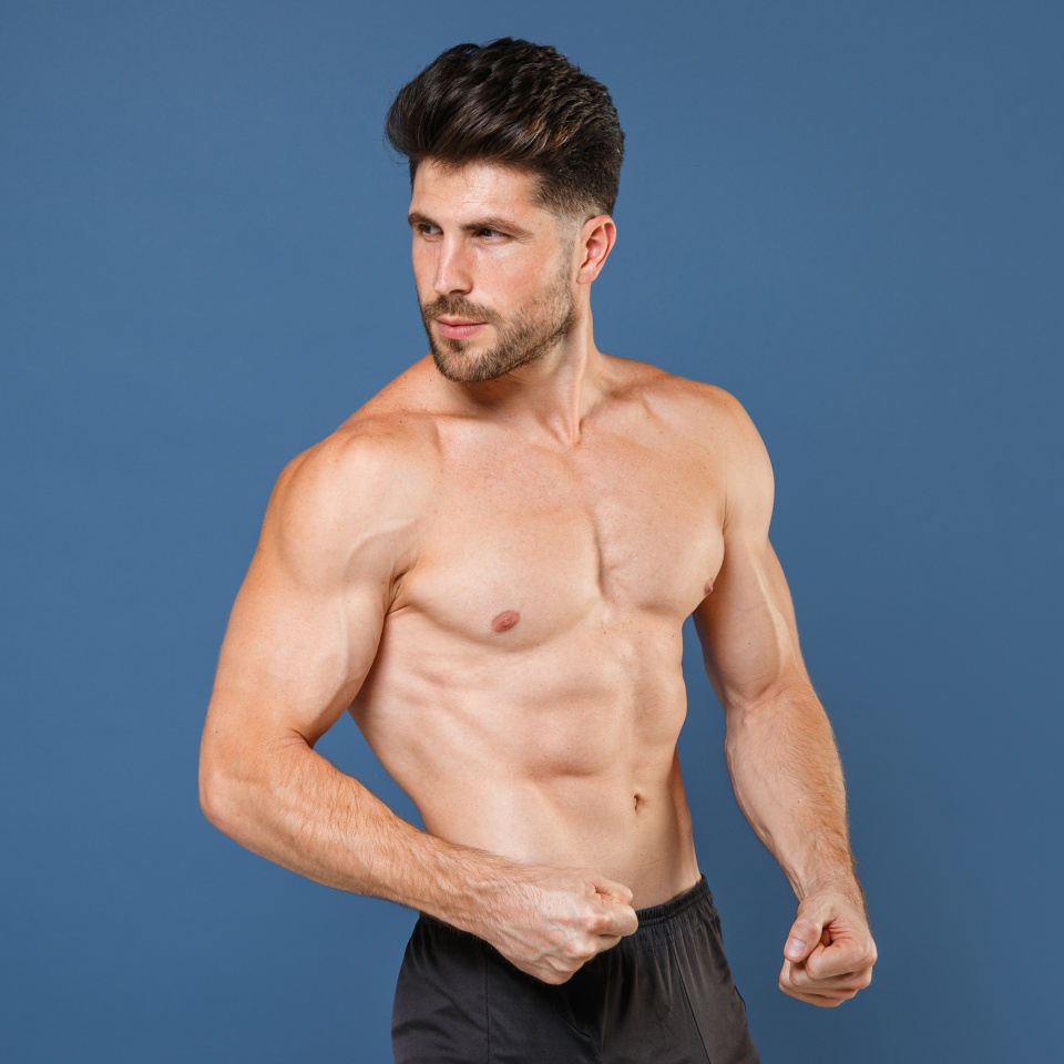 Young strong bearded fitness trainer instructor sporty bare-chested man sportsman he spend time in home gym look aside back isolated on plain navy blue background studio. Workout sport fit abs concept
