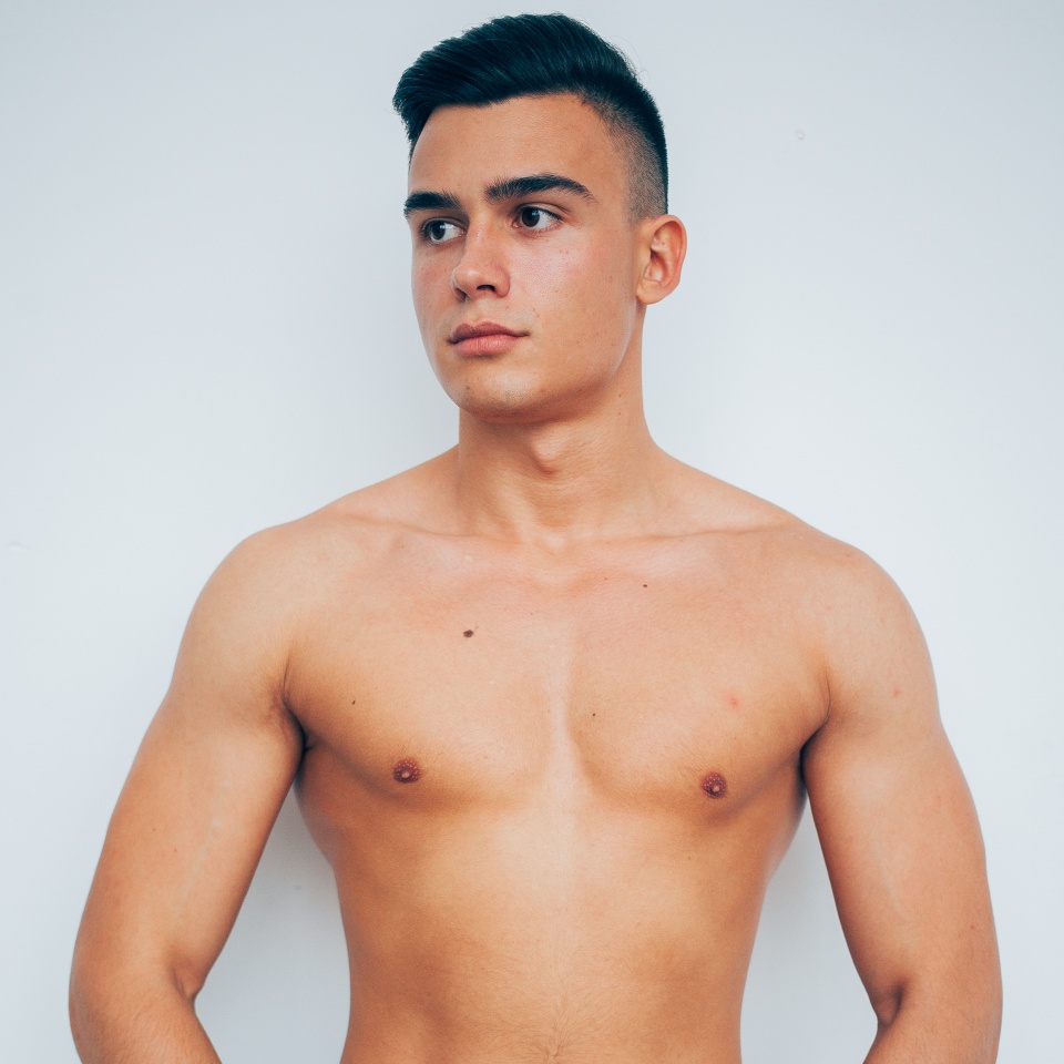 man is athletic with bare-chested, in jeans on the white background of the wall